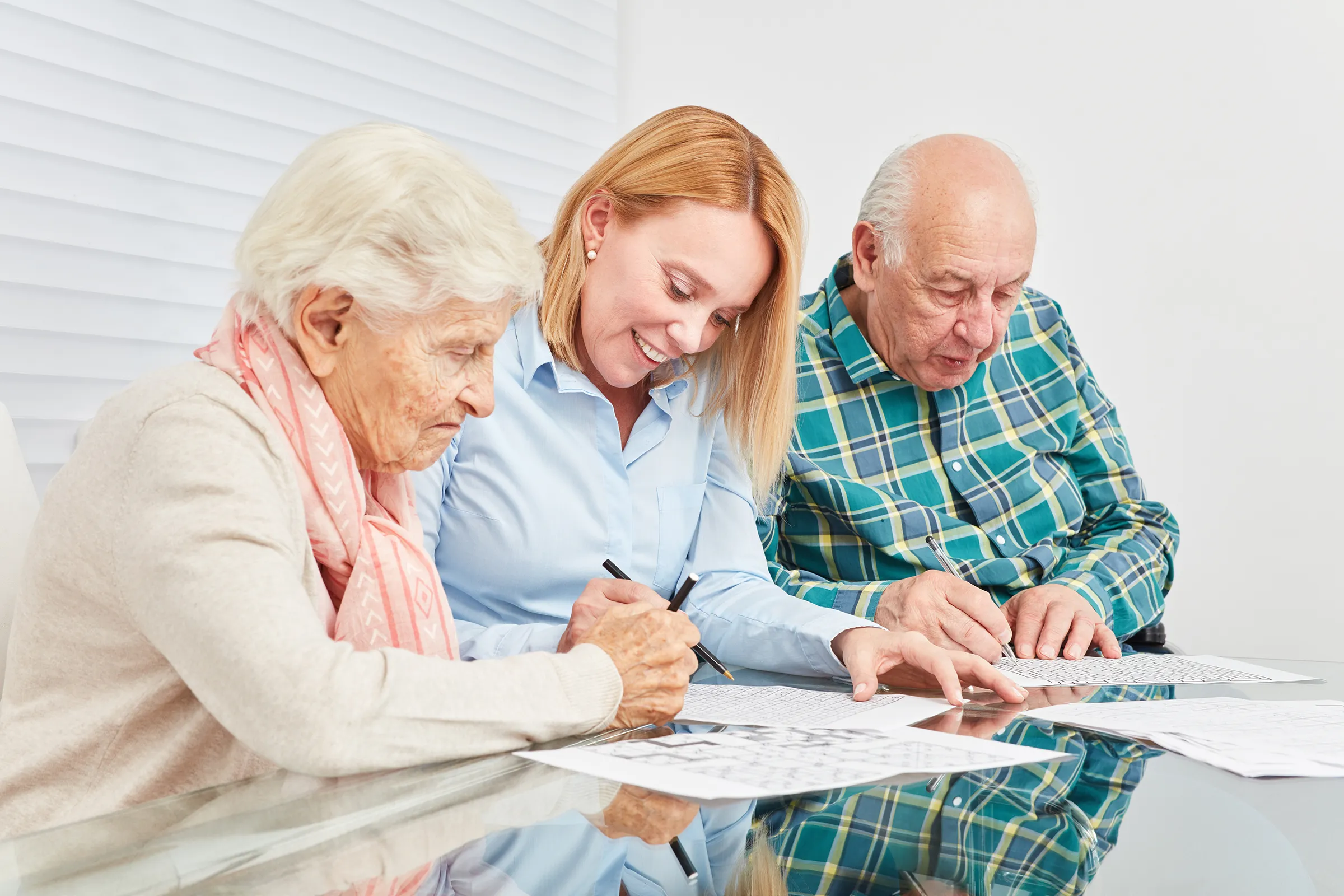 woman helping senior couple do crossword puzzles