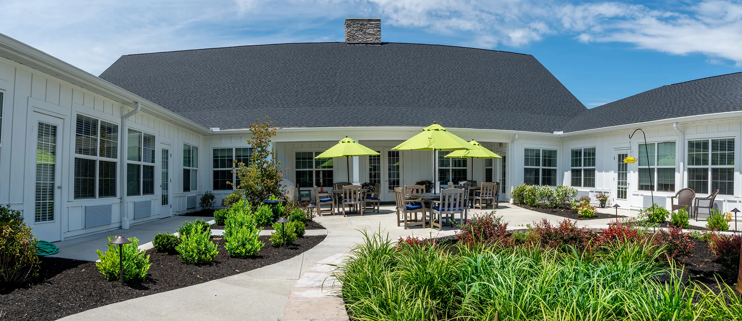 patio with greenery and tables with umbrellas at senior living facility