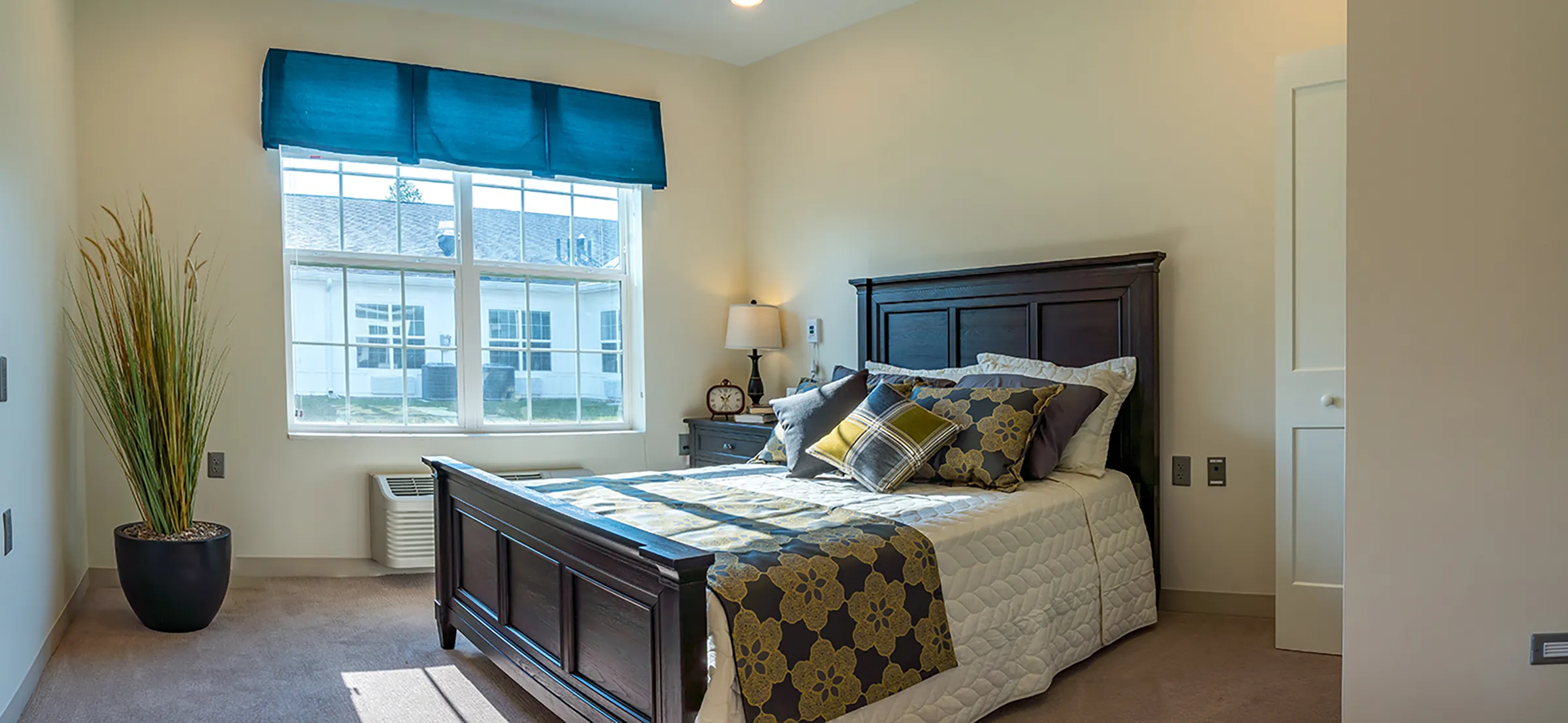 bedroom in assisted living facility with double bed and colorful pillows with natural light