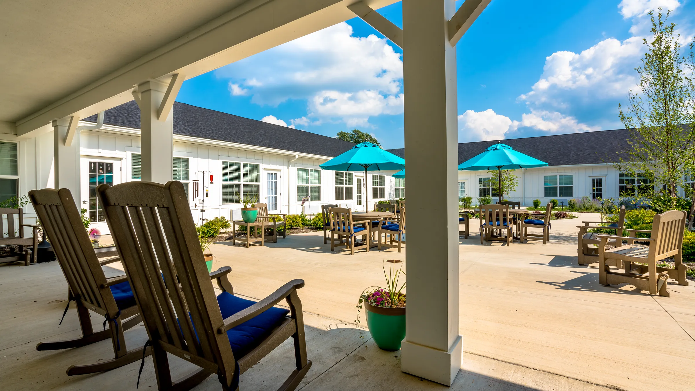 patio with multiple tables with umbrellas at senior living community