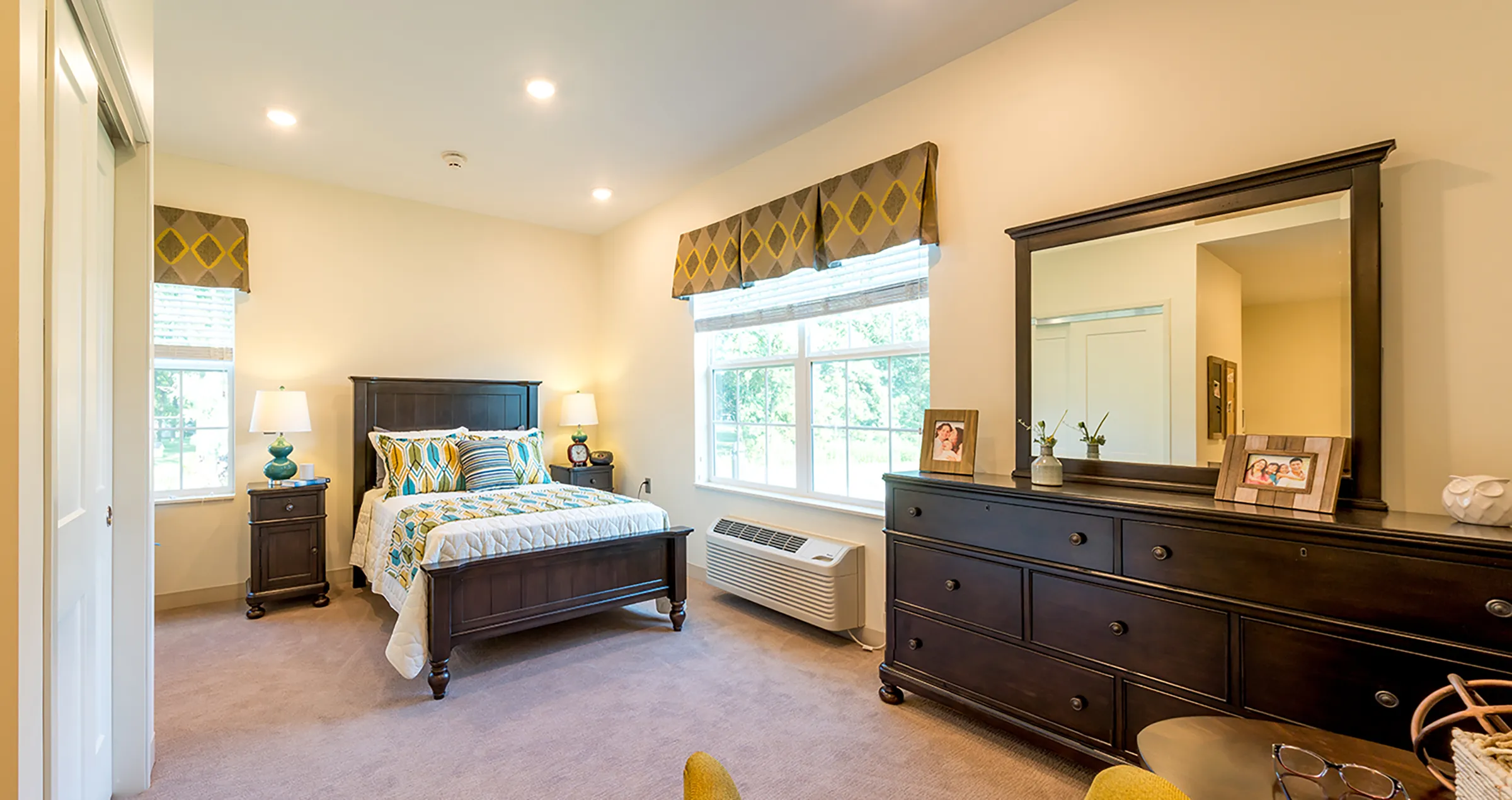 bedroom in assisted living community with colorful accessories and large dresser with sitting area