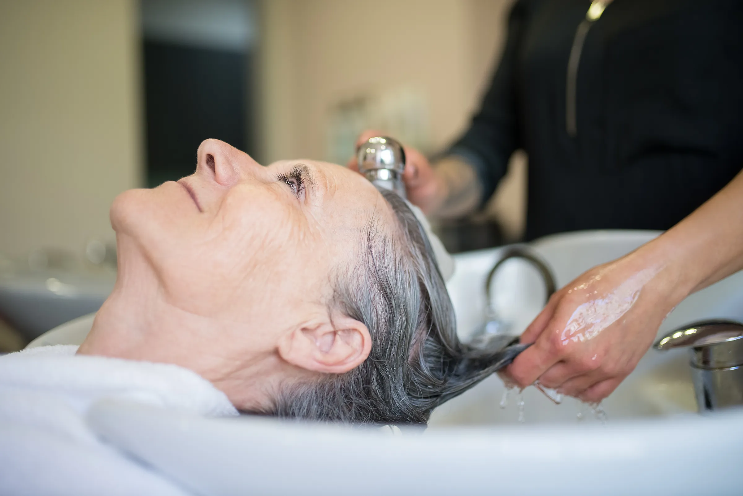 woman having her hair shampooed at salon in senior living facility