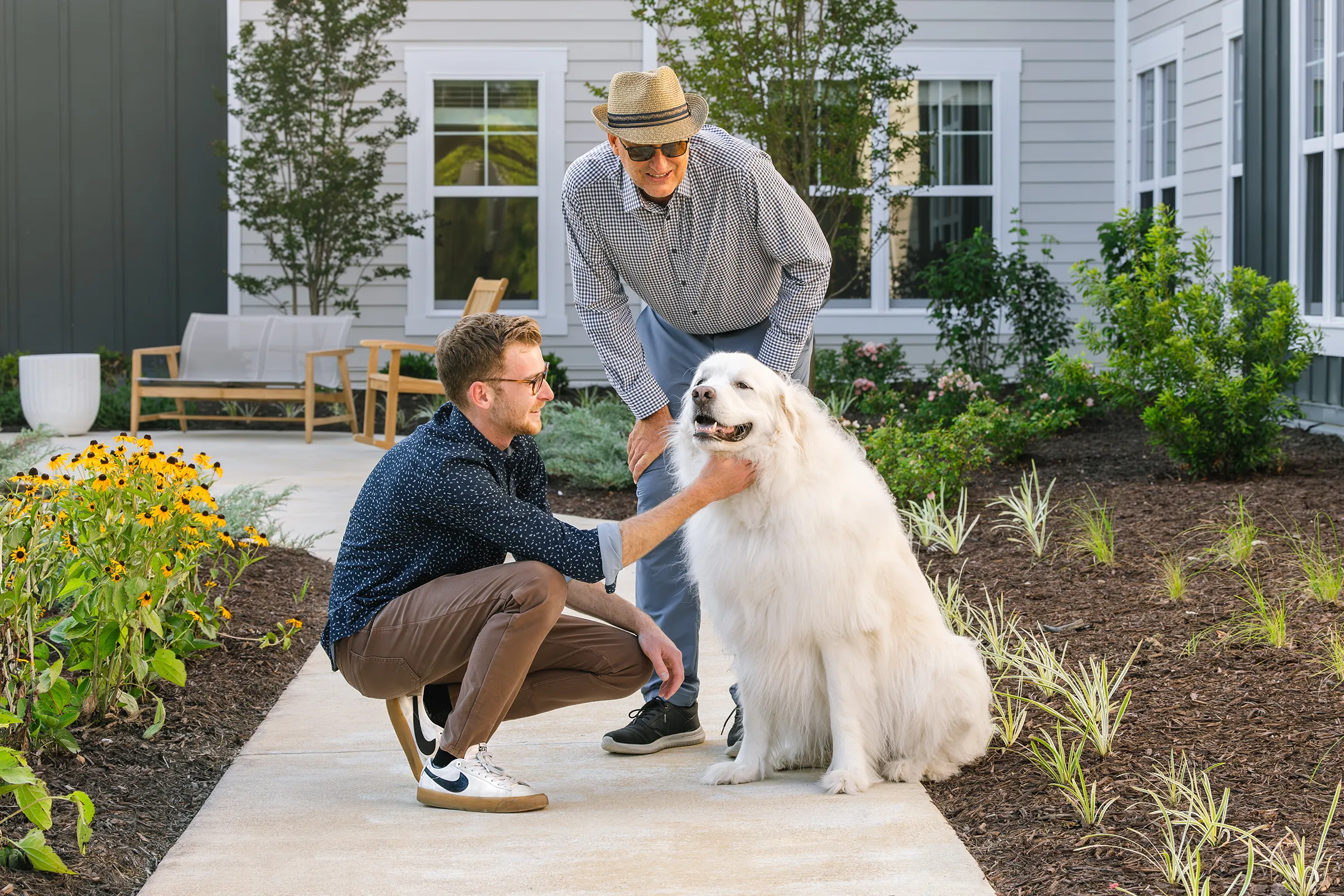 Senior man with his adult grandson petting a large white dog