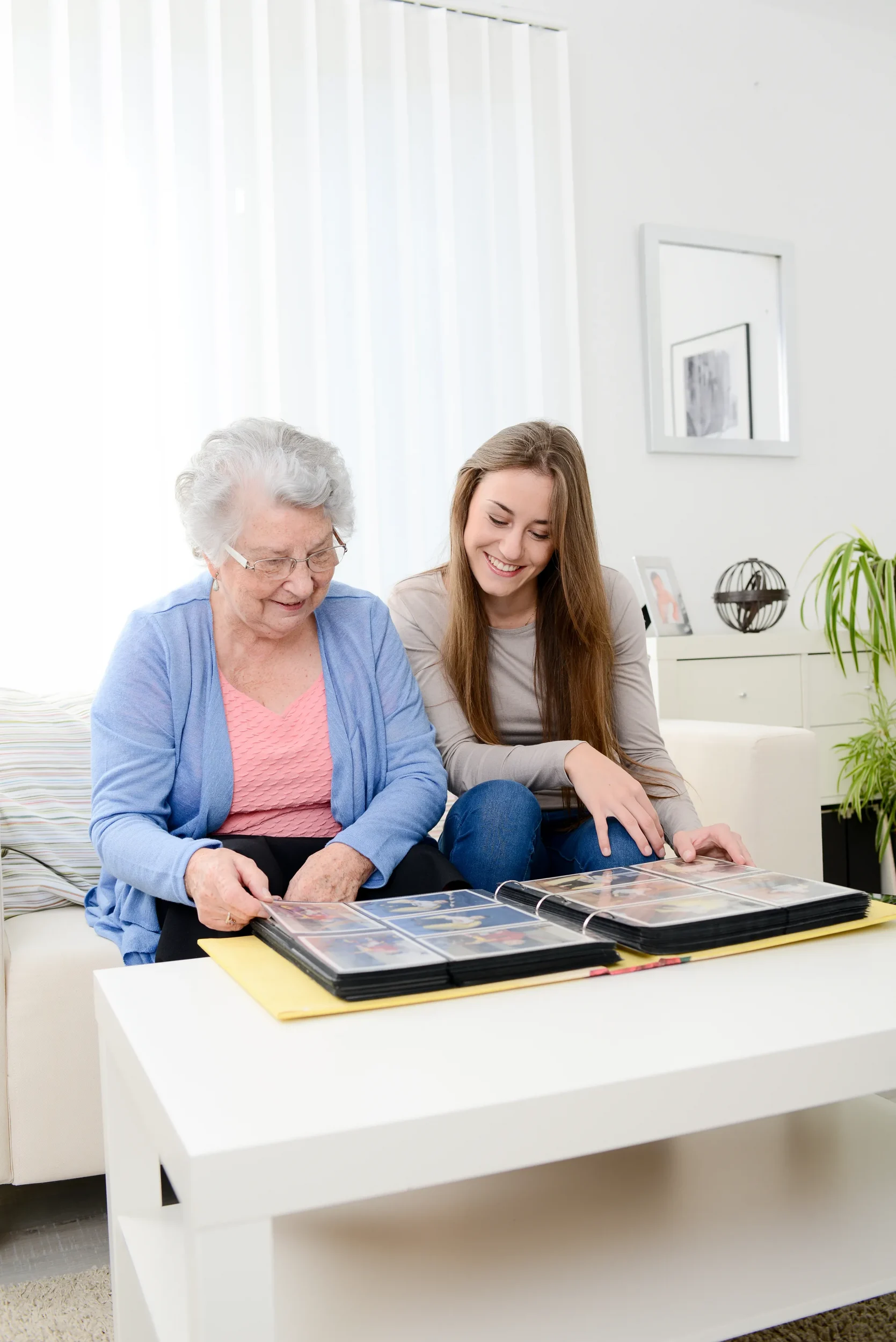 older woman with younger woman sitting on couch looking at photo albums
