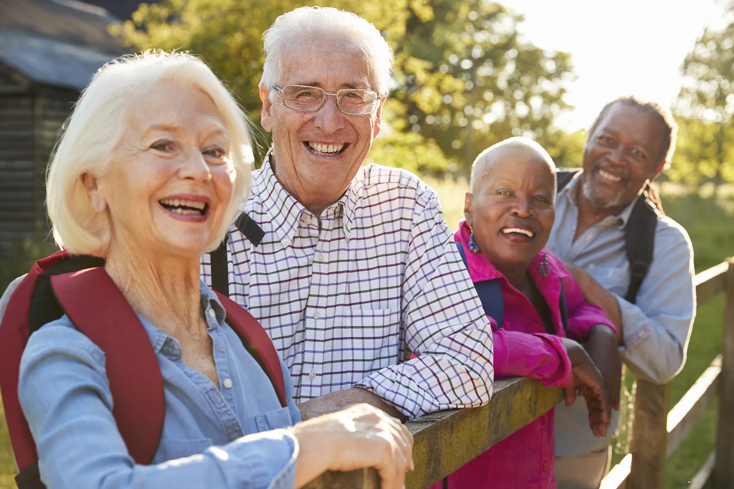 group of senior citizens leaning on fence outside smiling