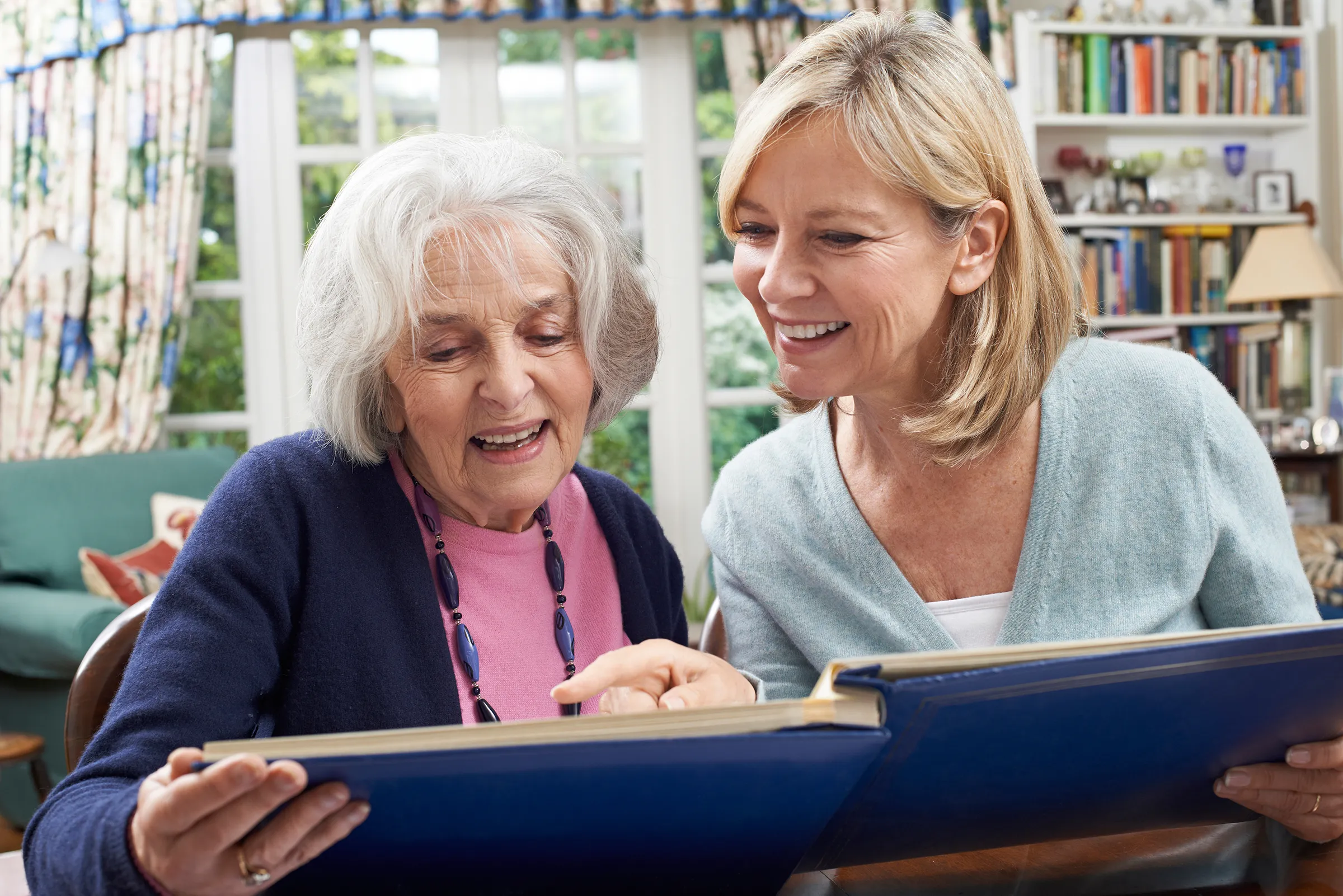 older woman and daughter looking at family photo album smiling