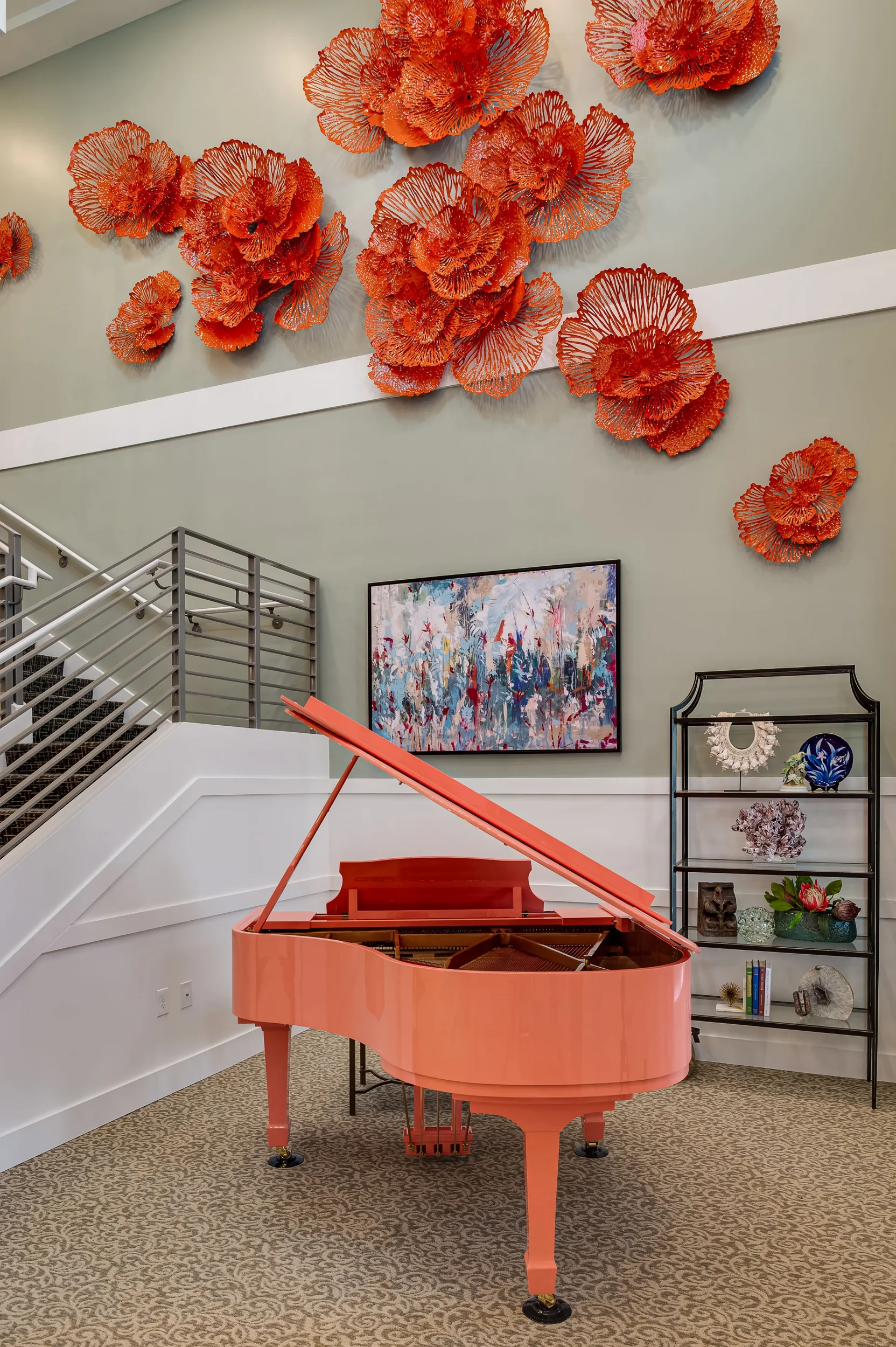coral colored baby grand piano with large floral art on walls