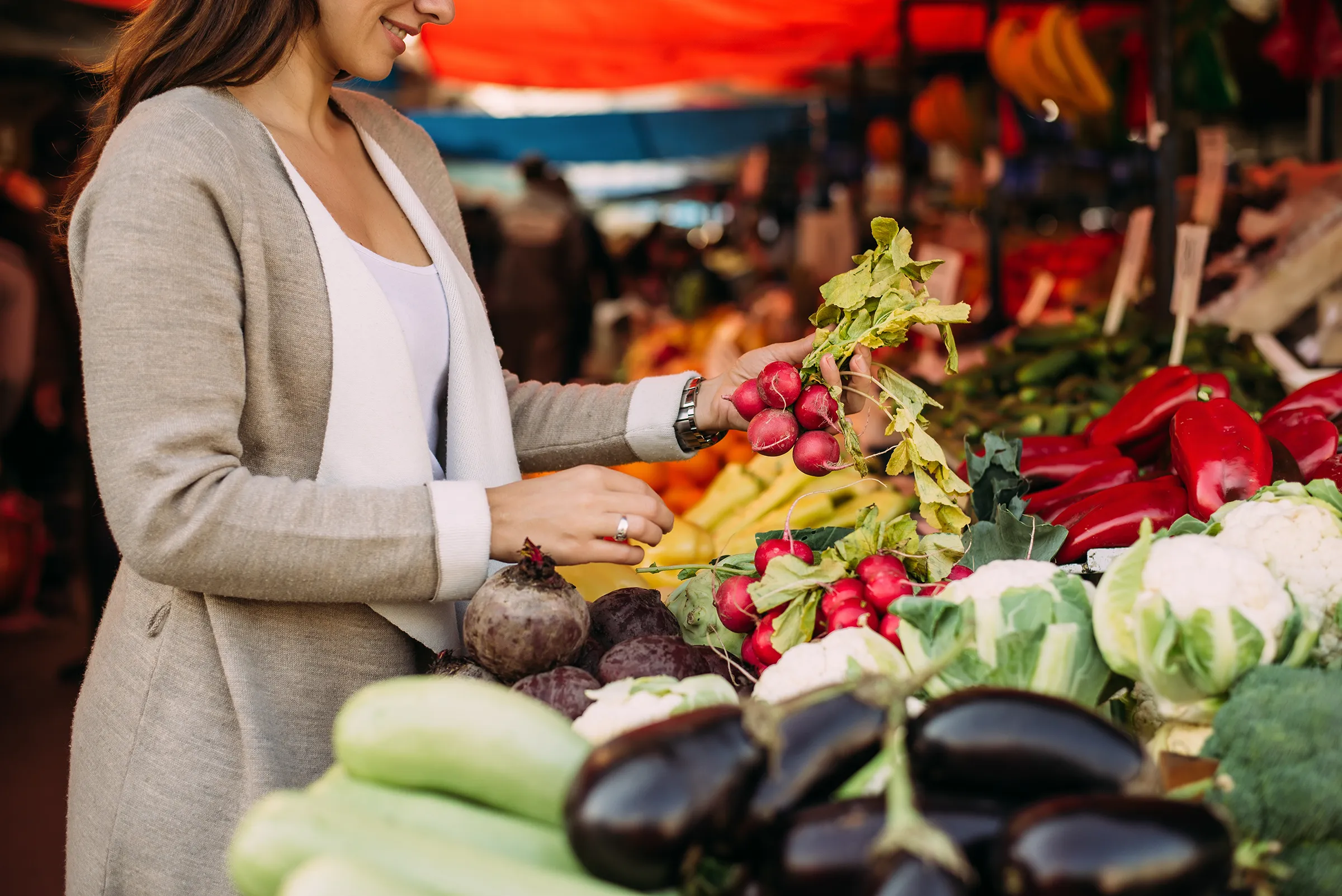 Woman smiling in farmers market with fresh vegetables